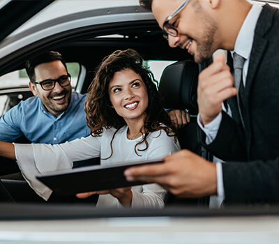 Eine Frau und ein Mann im Auto schließen einen 100.000-Euro-Kredit für ihren Traumwagen ab.