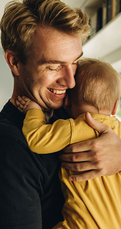 Ein Mann hält glücklich sein Kleinkind in den Armen