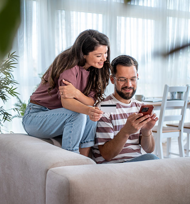 Ein junges Paar sucht auf dem Smartphone nach Angeboten für einen 50.000-Euro-Kredit.