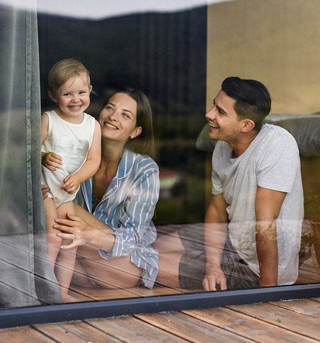 Eine junge Familie sitzt am Fenster ihres Eigenheims