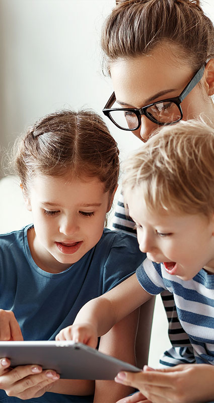 Eine junge Frau mit zwei Kindern sucht am Tablet einen geeigneten Konsumentenkredit.