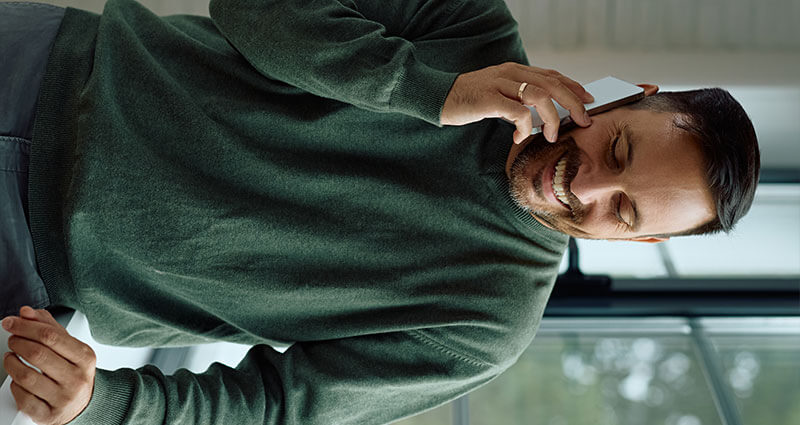 Ein lächelnder Mann am Telefon freut sich über seinen 100.000-Euro-Kredit.