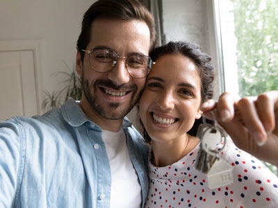 Ein Paar hält glücklich einen Haustürschlüssel in der Hand