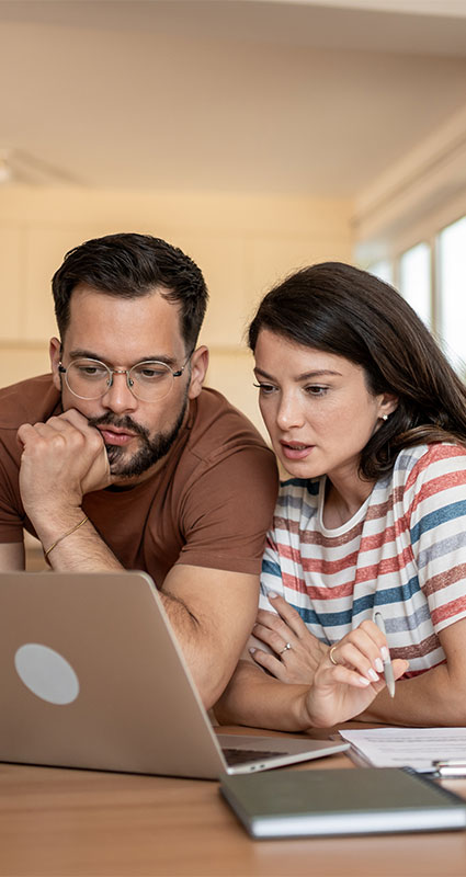 Ein Paar sucht auf dem Laptop online nach einem günstigen 50.000-Euro-Kredit.