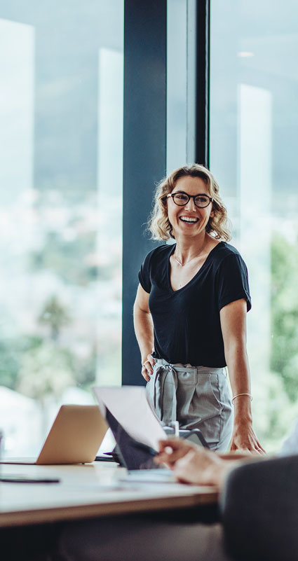 Eine Frau steht lachend an einem Konferenztisch