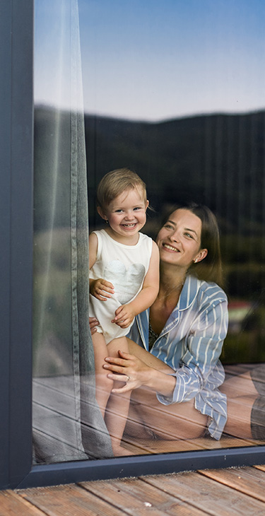 Eie Frau und ihr Kund schauen glücklich auf einem Fenster des Eigenheims