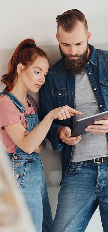 Paar informiert sich über Modernisierungskredit auf einem Tablet