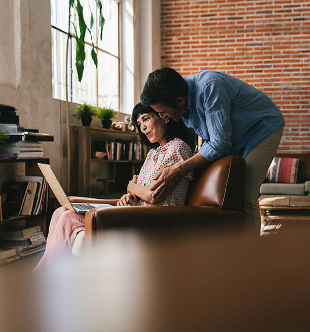 Per Nachrangdarlehen lassen sich Finanzierungslücken für das Wohneigentum schließen. Ein Ehepaar im Wohnzimmer freut sich über das neu abgeschlossene Nachrangdarlehen.