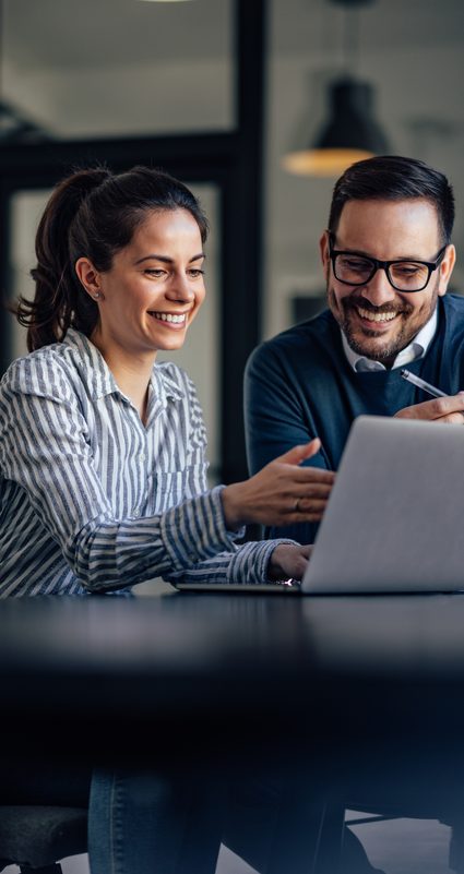 Zwei Personen im Büro schauen gemeinsam auf einen Laptop