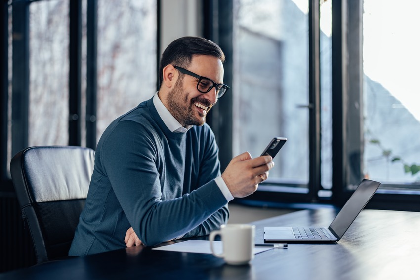 KREDIT.DE Partner lächelt und schaut auf sein Smartphone