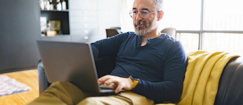 Ein Mann mit Brille informiert sich am Laptop über das Thema Bonitätsprüfung.