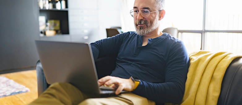 Ein Mann mit Brille informiert sich am Laptop über das Thema Bonitätsprüfung.