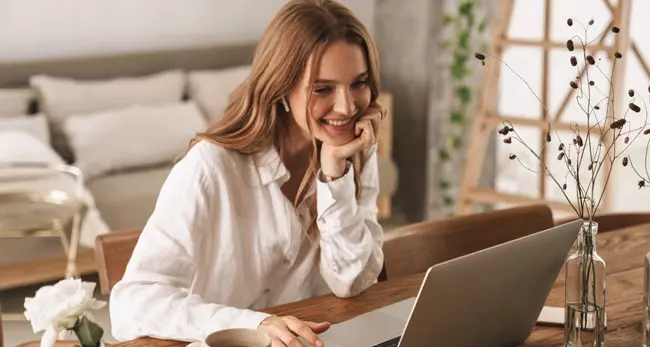 Eine Frau die glücklich auf einen Laptop schaut