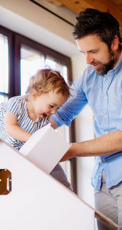 Ein Mann und ein Kind spielen im Eigenheim - es wurde mit einem Baufinanzierungsrechner geplant.
