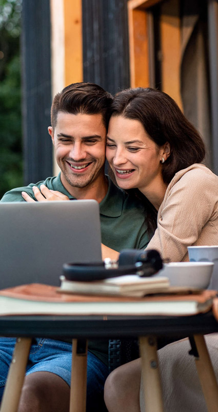 Ein Paar schaut auf einen Laptop und freut sich über die günstigeren Konditionen des Eigentümerdarlehens