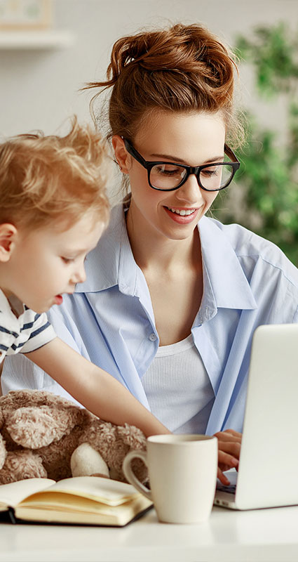 Eine junge Frau mit Kind sucht am Laptop einen geeigneten Konsumentenkredit.