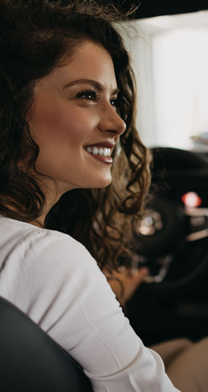 Eine Frau auf dem Beifahrersitz freut sich über ihren günstigen Autokredit